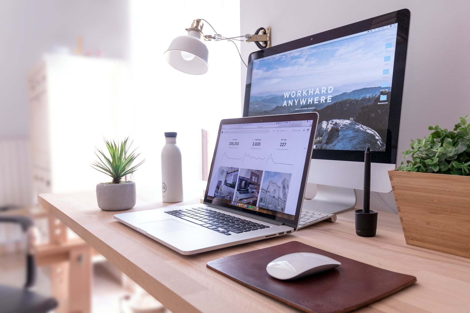 Independent designer's workspace: laptop, sketchbook and coffee on a wood desk